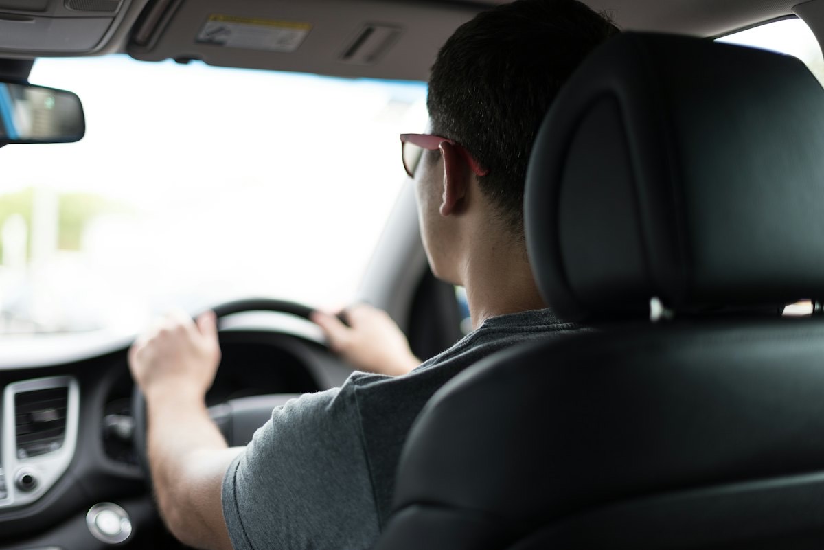 A man driving, seen from the back seat