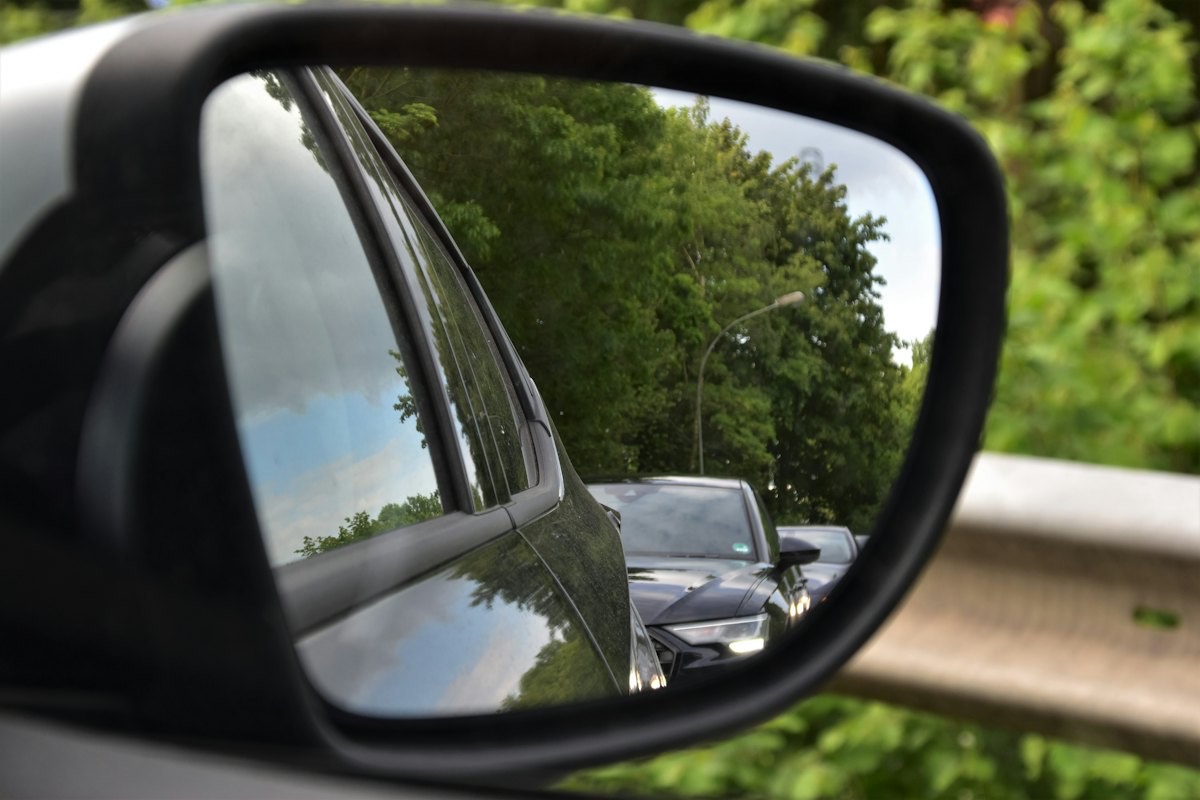 A car's side mirror reflecting the road behind